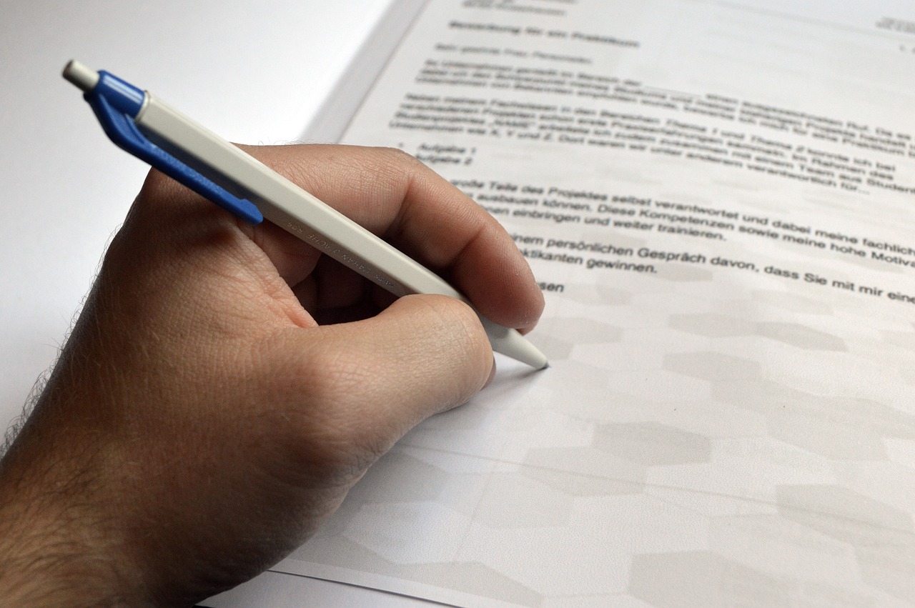 Presentare una domanda, immagine generica di mano che firma con una biro un modulo Presentare una domanda, immagine generica di mano che firma con una biro un modulo