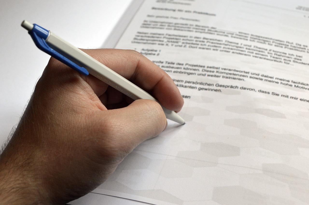 Presentare una domanda, immagine generica di mano che firma con una biro un modulo Presentare una domanda, immagine generica di mano che firma con una biro un modulo